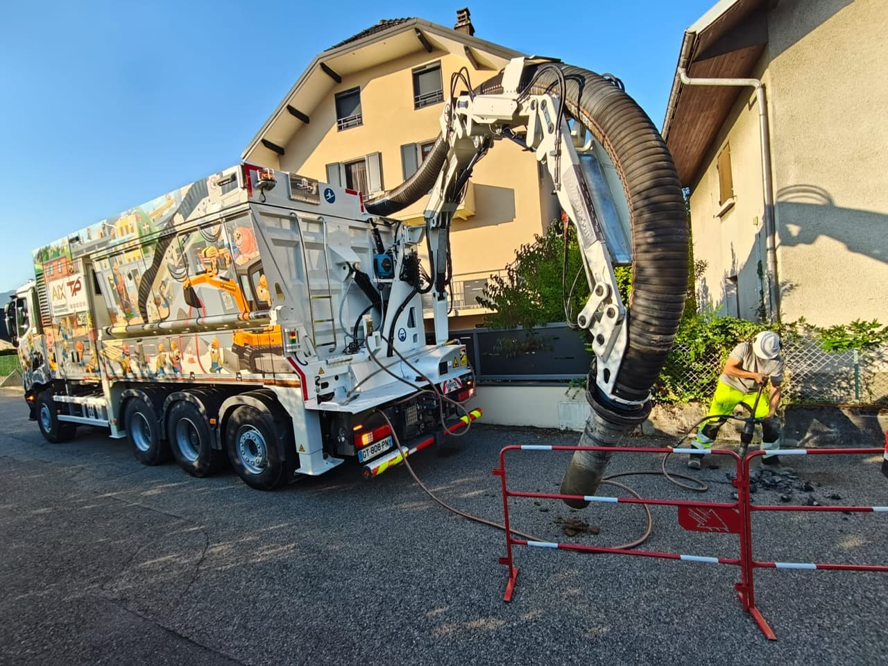 Aspiratrice-excavatrice AIX TP, bras d’aspiration déployé au-dessus d’une zone balisée dans une rue résidentielle