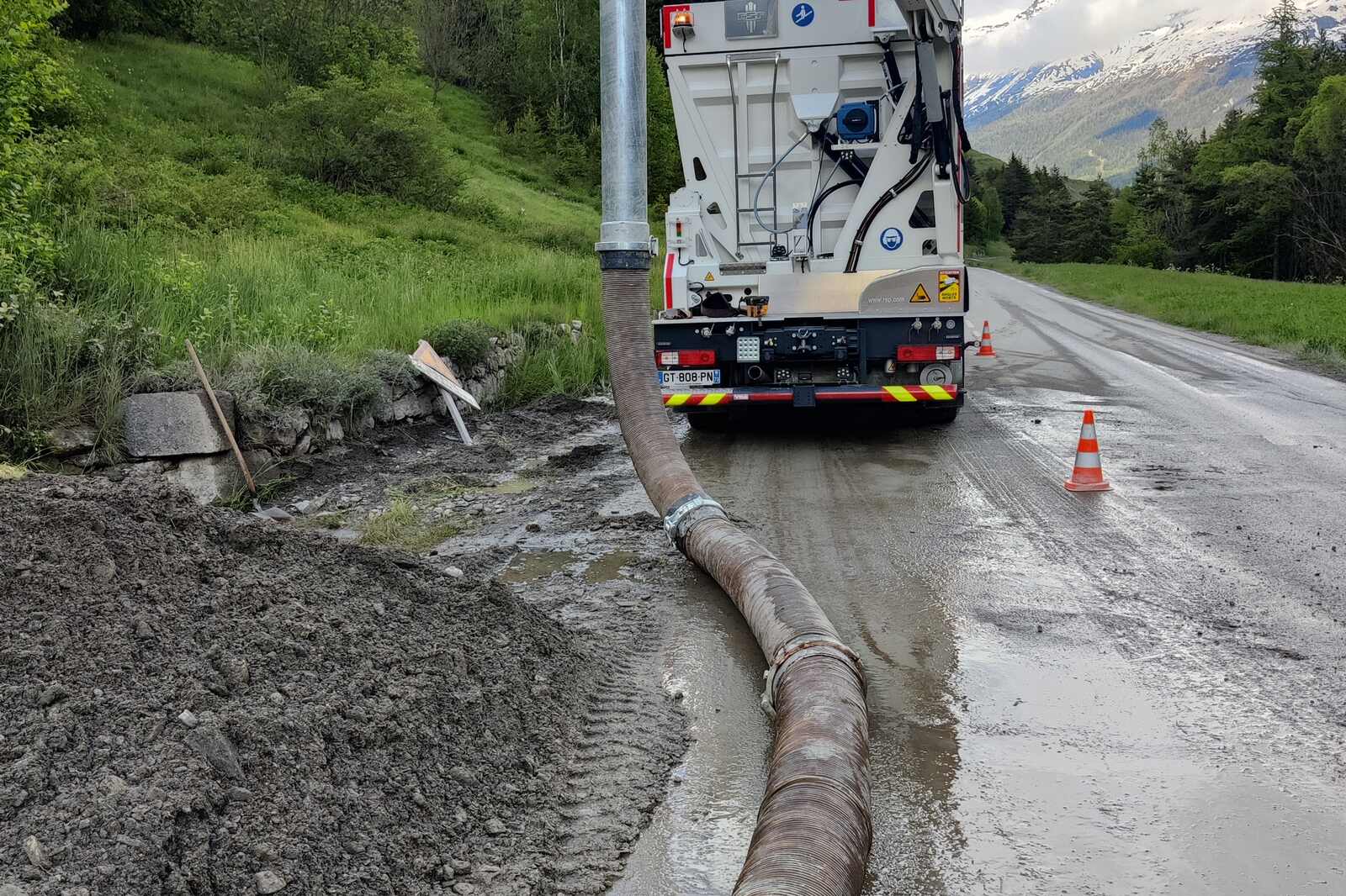 Aspiratrice et long tuyau d'aspiration déployé au bord d'une route de montagne au printemps