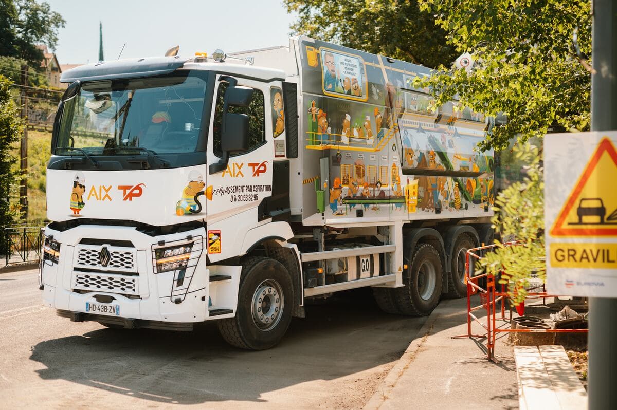 Camion aspirateur stationné en voirie, signalisation temporaire en place