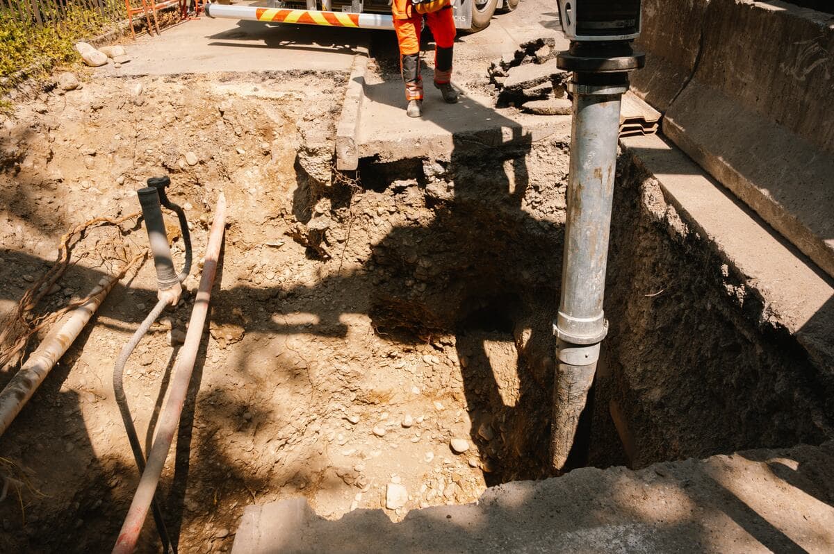 Tube d'aspiration plongeant dans une tranchée le long d'une canalisation