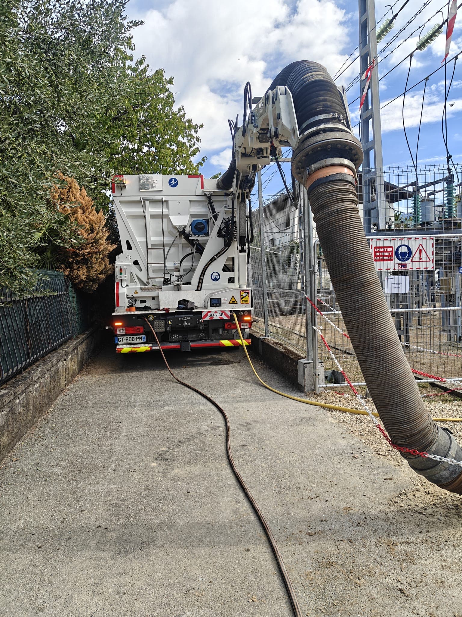 Aspiratrice-excavatrice AIX TP stationnée dans un accès étroit le long de la clôture du poste électrique