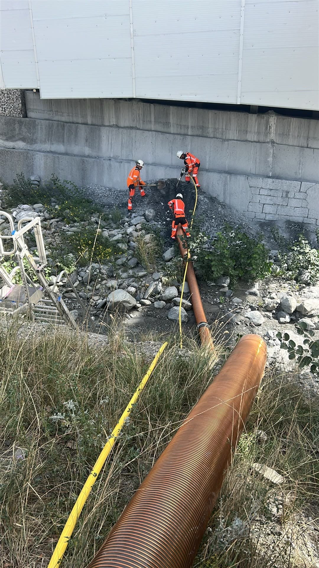 Opérateurs AIX TP aspirant des cailloux en lit de rivière asséché pour Campenon Bernard à Saint-Martin-la-Porte