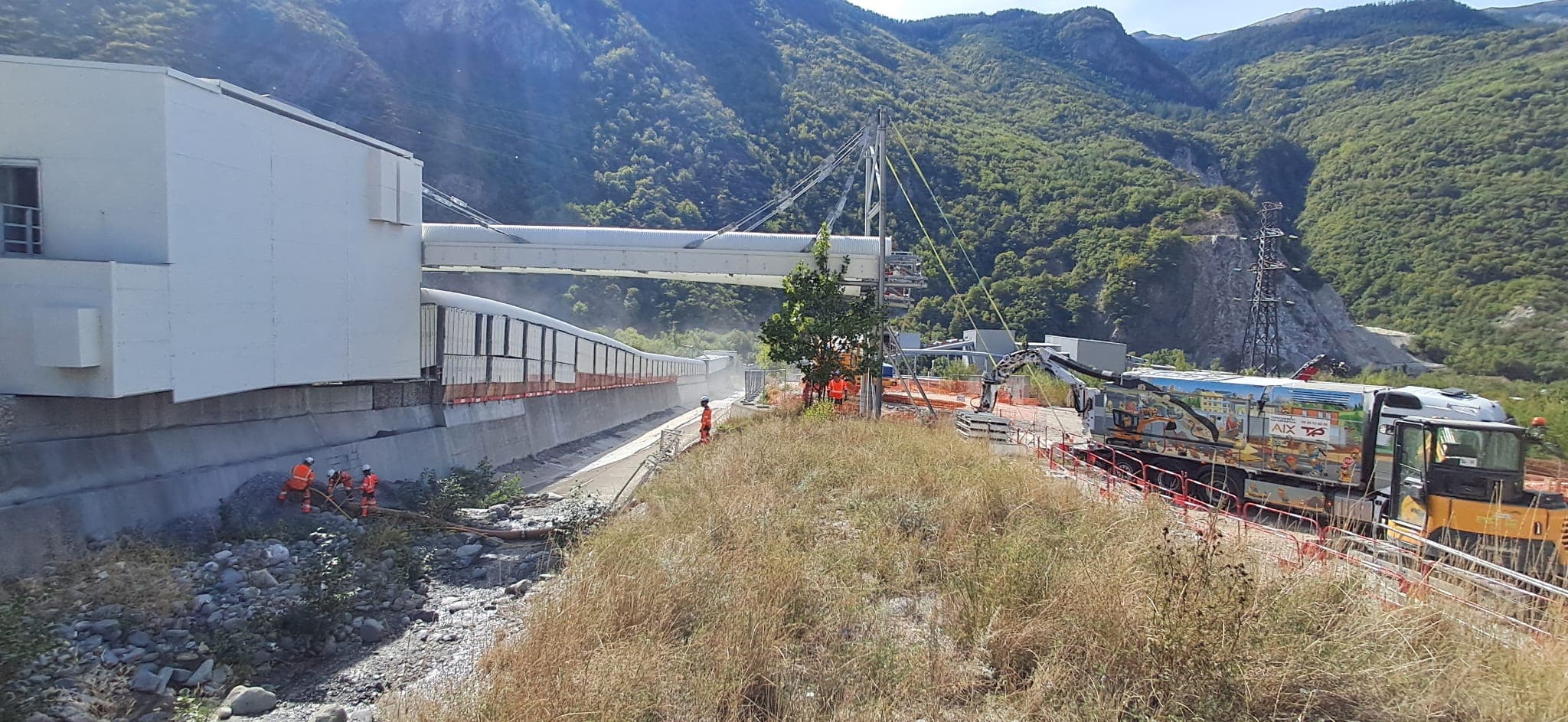 Vue d'ensemble du chantier TELT CO7 à Saint-Martin-la-Porte : aspiratrice-excavatrice AIX TP et opérateurs en lit de rivière asséché