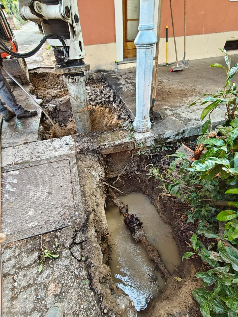 Fouille par aspiration sur un trottoir : canalisation d’eau dégagée et noyée par la fuite, à proximité d’un bâtiment