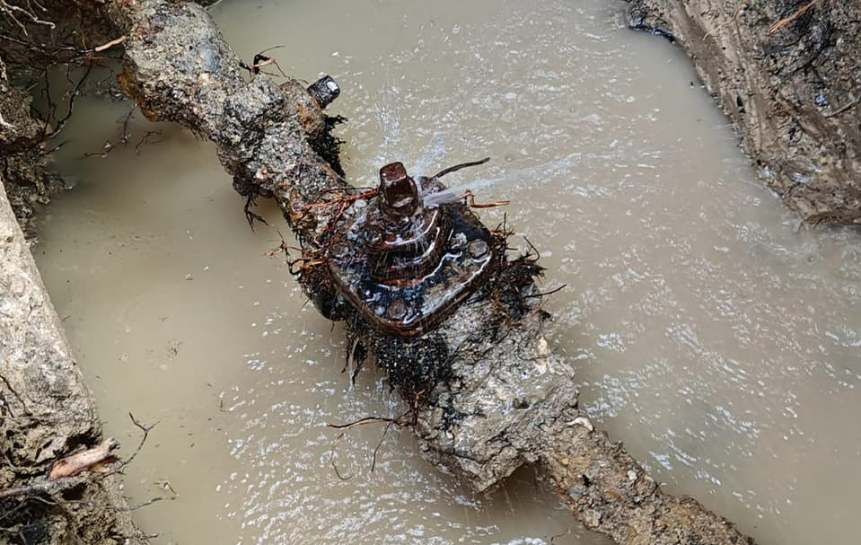 Fuite d’eau sous pression au niveau d’un joint boulonné sur une canalisation ancienne mise à nu par aspiration