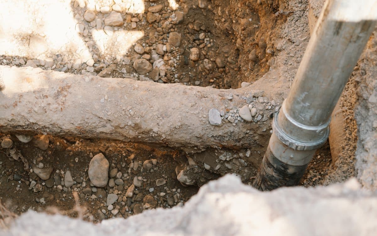 Gros plan sur la buse d'aspiration longeant une canalisation dégagée dans le terrain