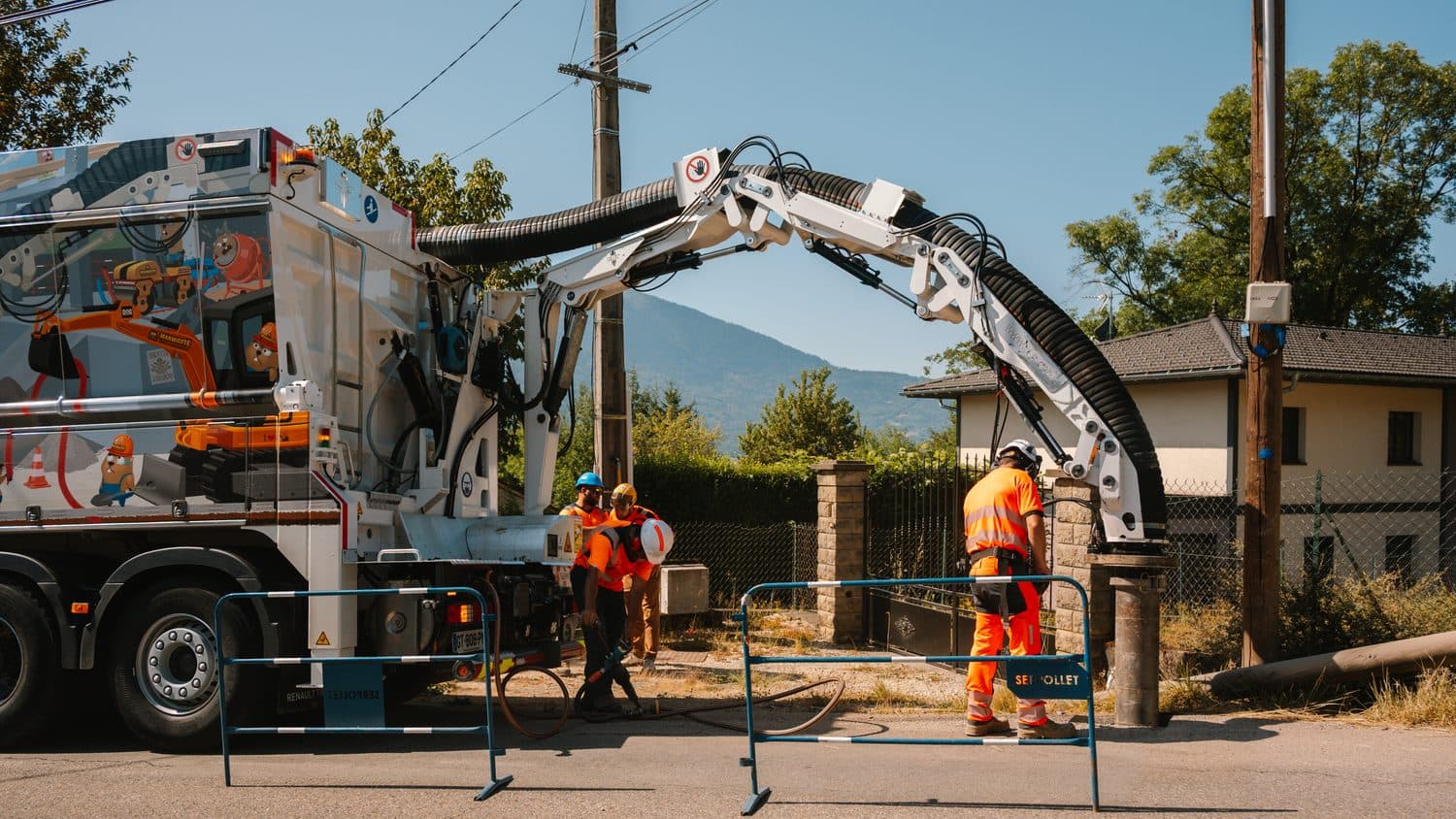 Camion aspirateur AIX TP bras déployé sur un chantier de réseaux, barrières de chantier installées en bord de chaussée